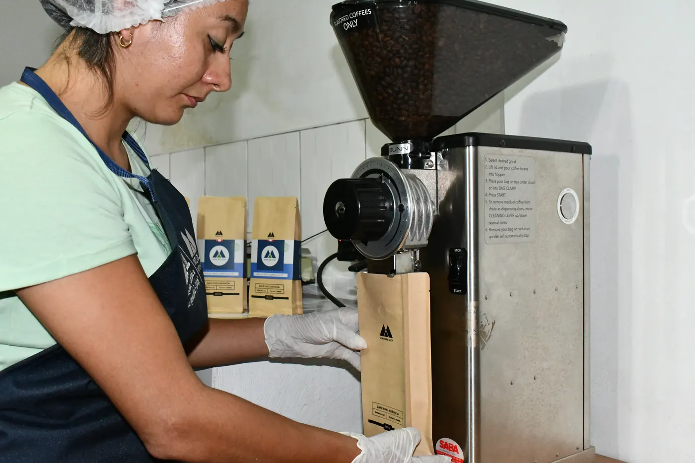 Trabajadora de la cooperativa moliendo café en la planta